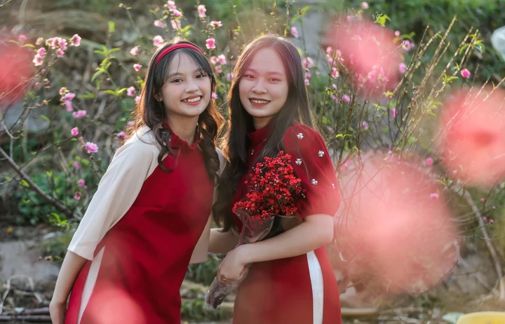 Hai bạn trẻ diện áo dài chụp ảnh cùng với hoa đào Nhật Tân. (Ảnh: Ngô Nhung)